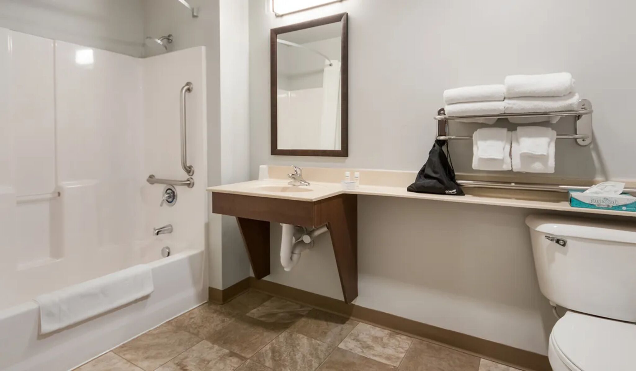 A bathroom with a bathtub, a sink with a mirror, and a toilet.