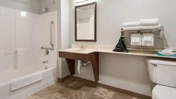 A bathroom with a bathtub, a sink with a mirror, and a toilet.