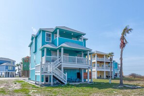Un edificio a più piani fronte spiaggia con balconi e un portico coperto.