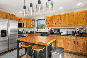 A modern kitchen with wooden cabinets, stainless steel appliances, and a central island with stools.