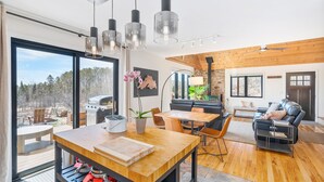 Un espace de vie moderne comprenant une table à manger en bois, un canapé et un barbecue à l’extérieur.