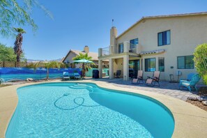 A swimming pool with clear water, surrounded by a patio area with lounge chairs and umbrellas. - Hike, Bike, Explore! Mtn-View Tucson Home (Tucson)