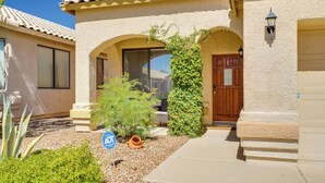 A residential building with a stucco exterior, a tiled roof, and a front door with a wooden panel. - Hike, Bike, Explore! Mtn-View Tucson Home (Tucson)