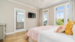 Ein Schlafzimmer mit Bett, Fernseher, Fenster und Blick ins Freie.