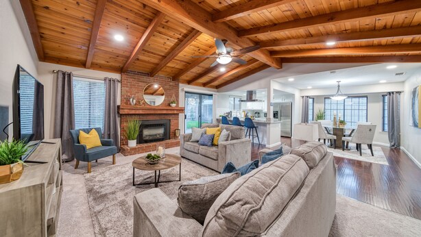 A spacious living room with a fireplace, sofas, and a ceiling fan. - Pool| Game Room|3/2|Sleeps 10:Class Act in Fresno! (Fresno)