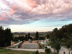 Ein Tennisplatz mit Pool, umgeben von Bäumen und Hügeln im Hintergrund.
