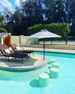 Ein Swimmingpool mit Liegestühlen und einer überdachten Sitzgruppe.