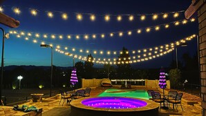 Eine Außenpatio mit Lichterketten, einem Billardtisch und Sitzbereichen.