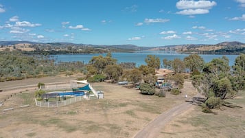 Una propiedad frente al lago con piscina, zona de picnic y área de juegos vallada.