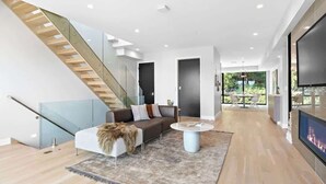 A modern living room with a staircase, a sofa, a coffee table, and a fireplace.