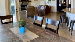Amplia sala de estar con chimenea, comedor con mesa y sillas de madera, y cocina con salpicadero de piedra.