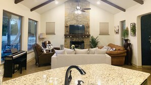 Una sala de estar amplia con chimenea de piedra, un televisor y un piano.