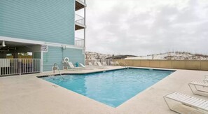 A rooftop pool with lounge chairs and a view of the beach.