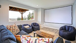 Ein gemütliches Wohnzimmer mit einer Couch, zwei Sitzsäcken, einem Couchtisch und einem großen Bildschirm.