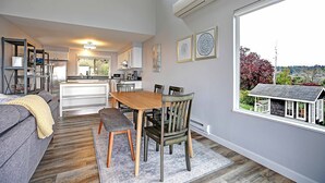 Eine moderne Küche mit weißen Schränken, einem Holzespeisetisch und einem großen Fenster mit Blick auf ein Haus.