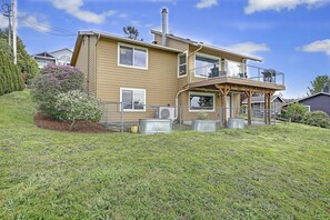 A two-story house with a balcony, a chimney, and a fenced yard with a small tree.