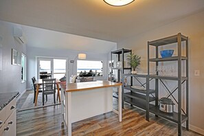A modern kitchen with a wooden island, a metal shelving unit, and a view to the outside.