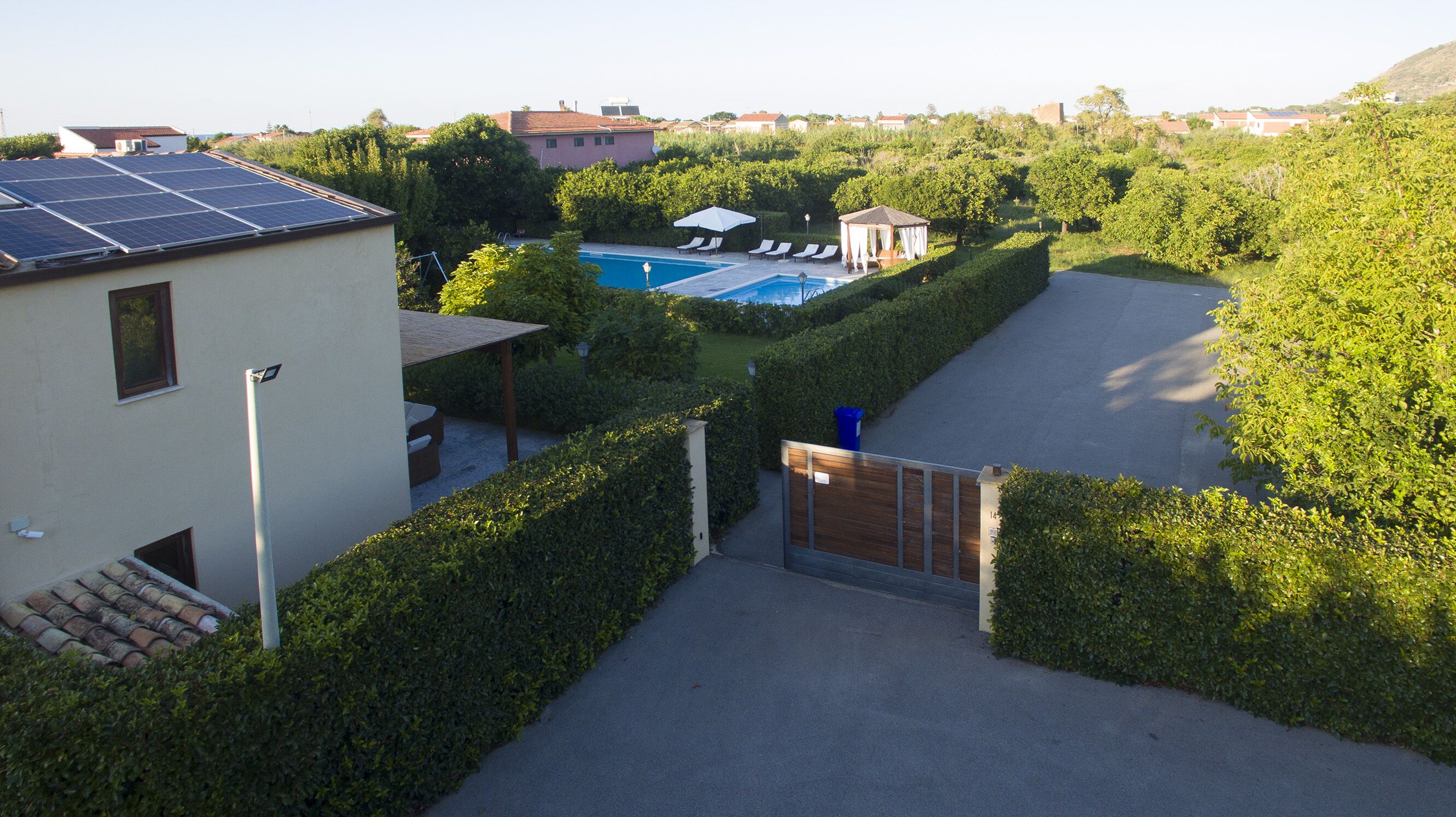 Un quartier résidentiel doté d’une piscine, de panneaux solaires et d’une entrée sécurisée par un portail.