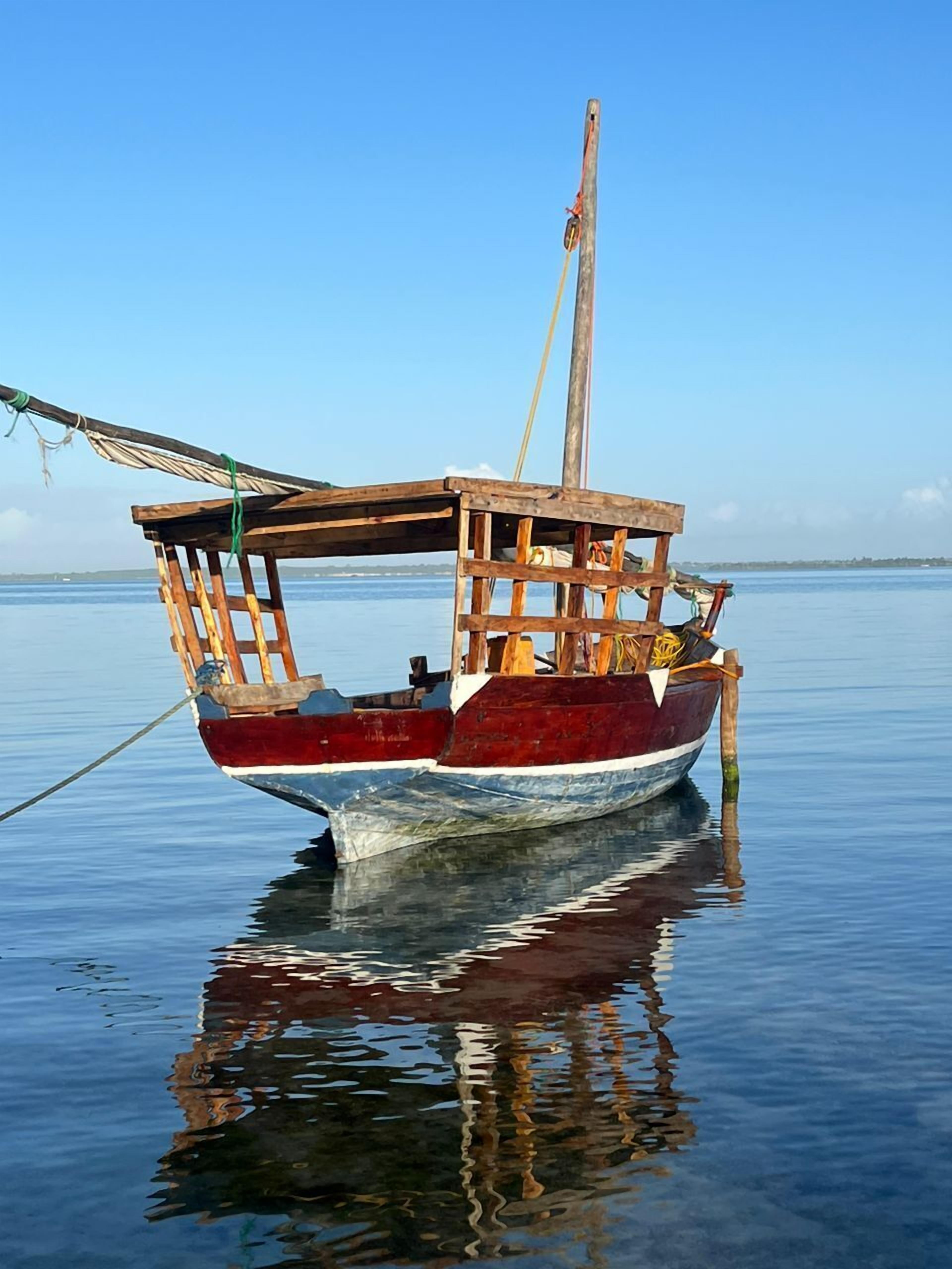 A wooden boat with a simple structure, anchored in calm water.