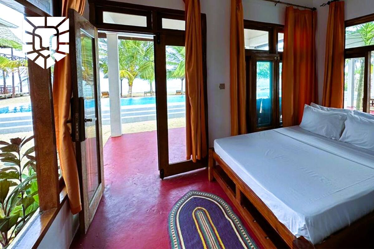 A hotel room with a bed, a view of the pool, and a door leading outside.