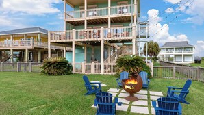 A multi-story building with a balcony, outdoor seating area with chairs, and a fire pit. - Savings Alert! Pet-Friendly: Spacious, Fenced Retreat, Views! Games!  Sleeps 14 (Crystal Beach)