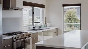 Una cocina moderna con una isla central, electrodomésticos de acero inoxidable y ventanas amplias que ofrecen vistas al exterior.