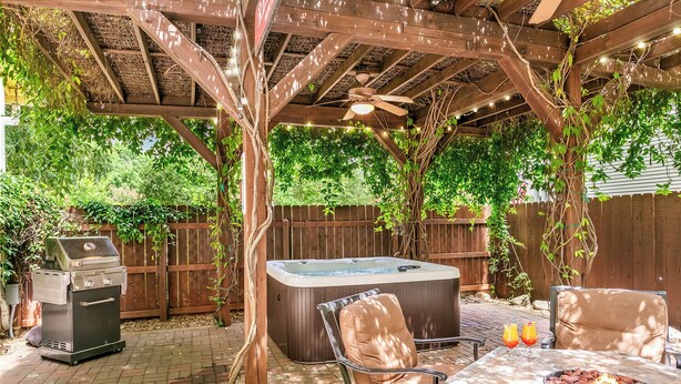 Patio esterno con idromassaggio, barbecue e tavolo con bevande.