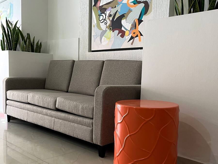 Una sala de estar moderna con un sofá gris, un sillón rojo de acento y un cuadro abstracto colorido en la pared.
