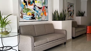 Una sala de estar moderna con un sofá gris, una mesa de centro de vidrio y arte abstracto en la pared.