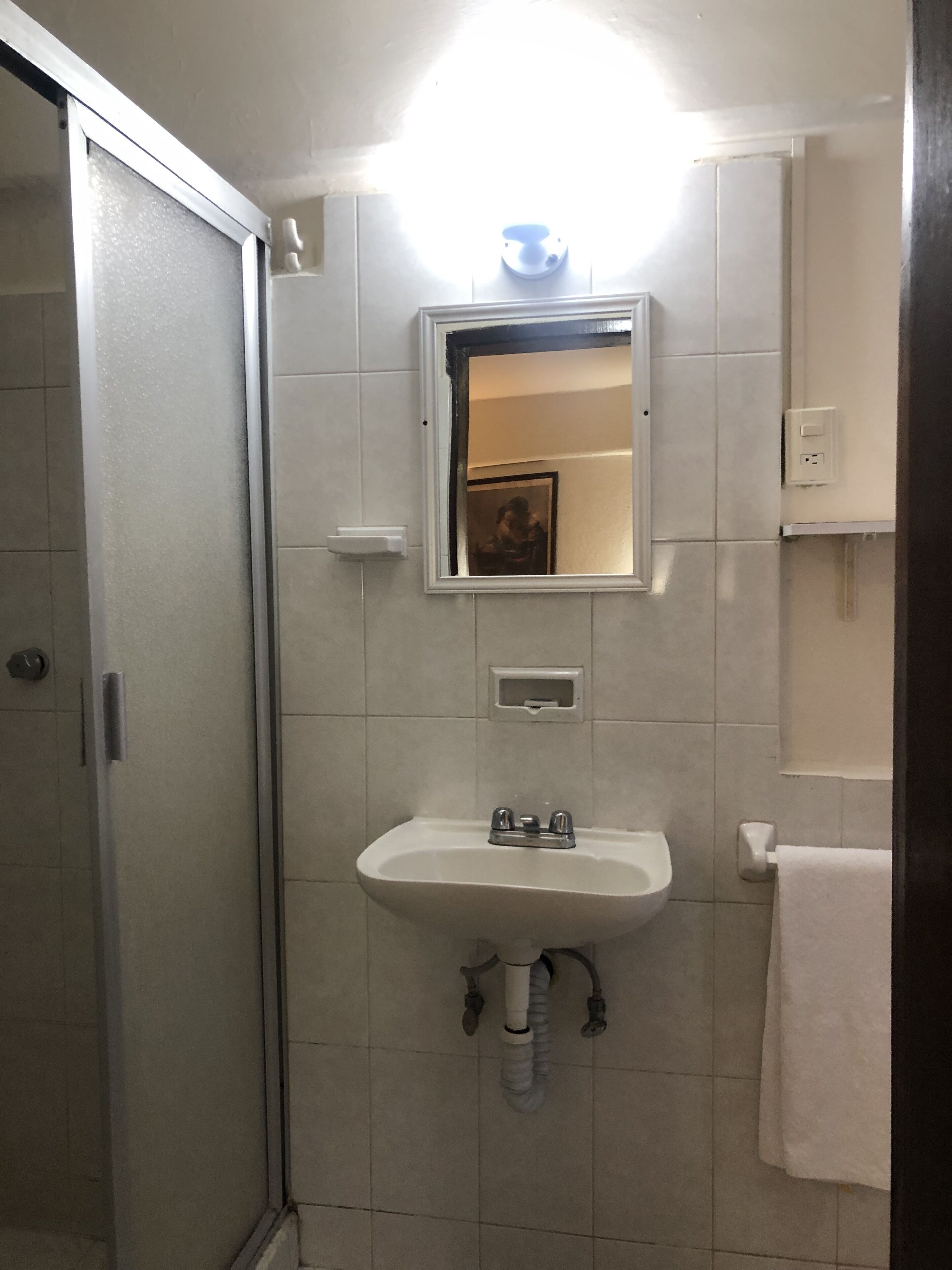 A bathroom with a shower, sink, and mirror.