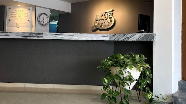 Zona de recepción de un hotel con un mostrador de mármol, un reloj y un letrero que dice "HOTEL TORINO".