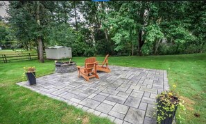 Relax in the serene backyard patio surrounded by lush trees and a beautifully manicured lawn.