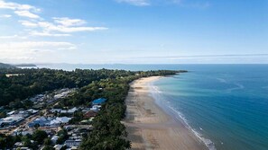 A coastal area with a beach, a residential area with houses, and a clear sky.
