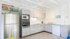 Eine moderne Küche mit Edelstahlgeräten, Holzschränken und einer gefliesten Spritzschutzwand.