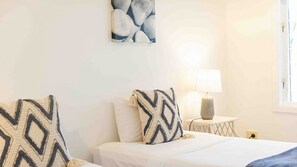 A bedroom with two beds, a nightstand with a lamp, and a wall art piece.