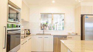 A modern kitchen with stainless steel appliances, a window with a view, and light-colored cabinetry.