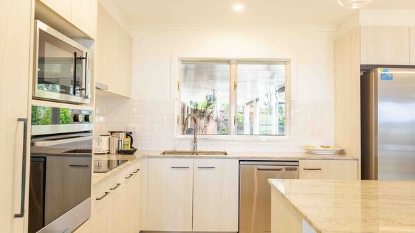 A modern kitchen with stainless steel appliances, a window with a view, and light-colored cabinetry.