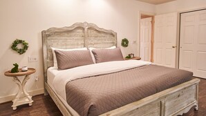 Une chambre à coucher avec une tête de lit en bois, une couvre-lit matelassée, deux tables de chevet et une porte sur le côté droit.