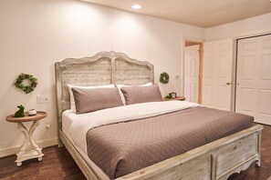 A bedroom with a wooden headboard, a quilted bedspread, two nightstands, and a door to the right.