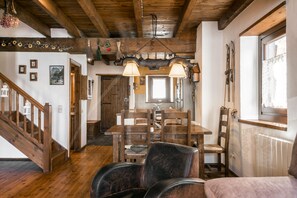 A wooden interior with a dining area, staircase, and a view of the outside.