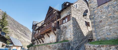 A stone building with wooden balconies and a staircase leading to an upper level.