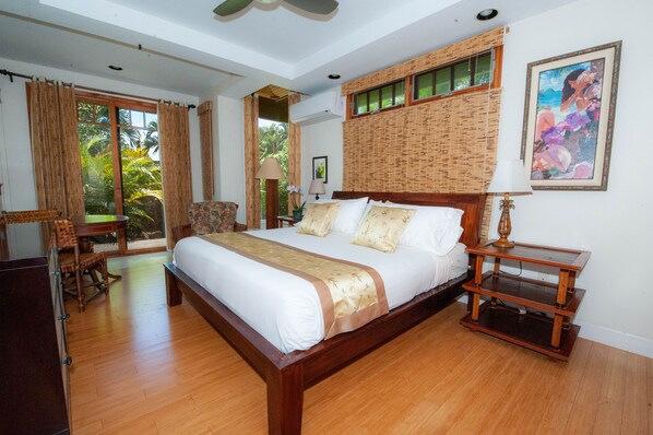 A spacious bedroom with a large bed, a wooden nightstand, and a view of the outdoors. - Tropical Rendezvous Suite - Luxury Studio in tropical gardens with koi ponds. (Koloa)