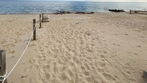Una playa arenosa con una cerca de madera y una barrera de cuerda.