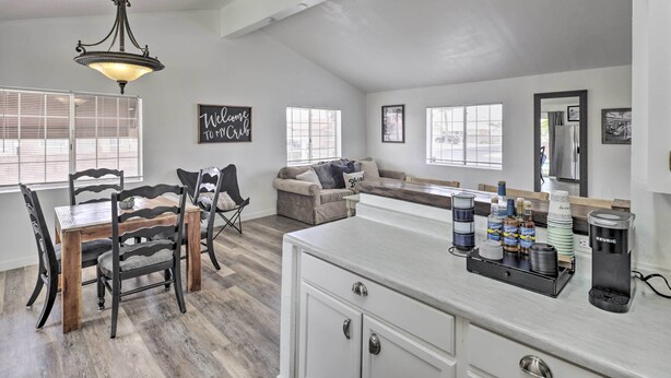 A spacious living area with a dining table, chairs, a sofa, and a coffee station.