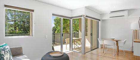 Una sala moderna con un sofá, un reposapiés y una zona de comedor con sillas y una mesa.