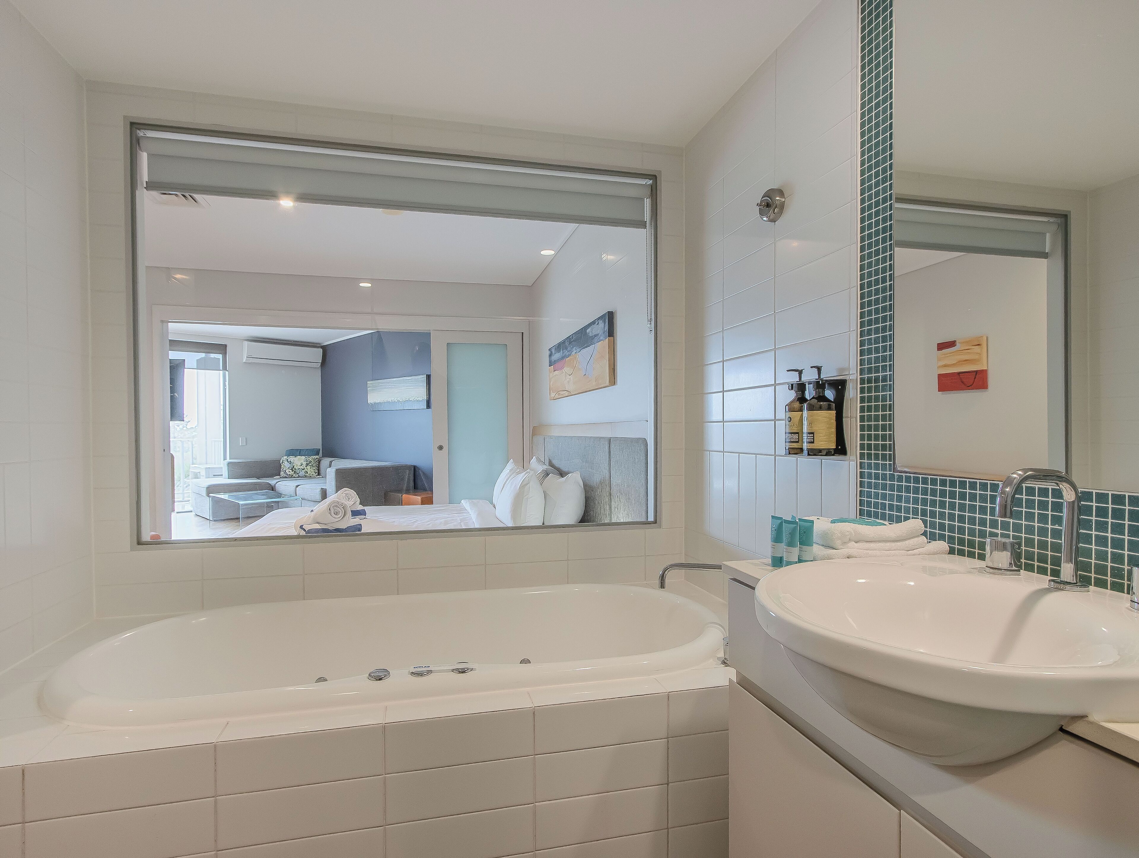 A modern bathroom with a large bathtub, a sink, and a mirror.