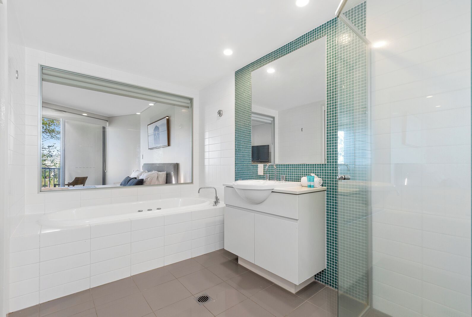 A modern bathroom with a large bathtub, a vanity with a sink, and a mirror.