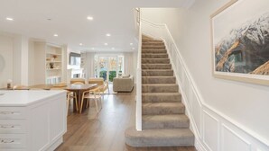 A spacious living area with a staircase, a dining table, and a kitchen area.