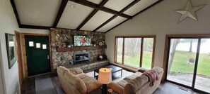 Ein Wohnzimmer mit Kamin aus Stein, einem großen Fenster und einer Sterndekoration an der Decke.