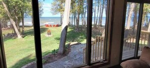 A view through a window with a lawn, trees, and a wooden deck. - Waterfront, Panoramic Views! White Star Point (Brussels)